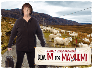 Woman with a red bob, with glasses is looking smug. She is wearing a black tracksuit with her hood up, holding a wheelie suitcase and has a backdrop of hills with sheep. 