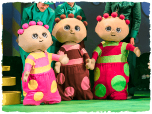 Three In The Night Garden characters stand together being played by puppetteers in green outfits