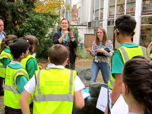 A group of school children stand around in a garden .