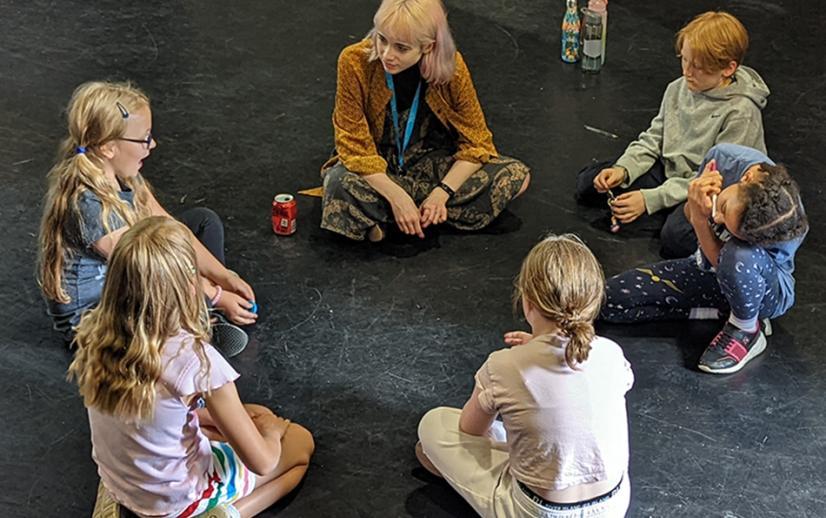 A group of children sit in a workshop
