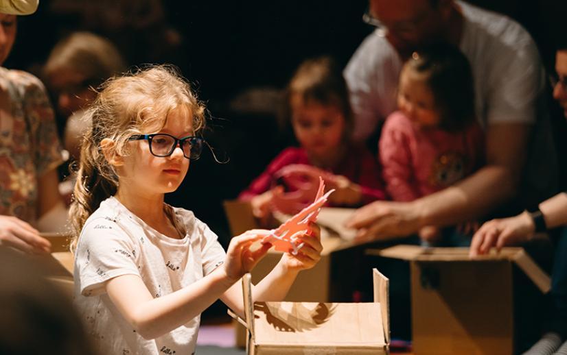 A young girl plays with a prop during a production.