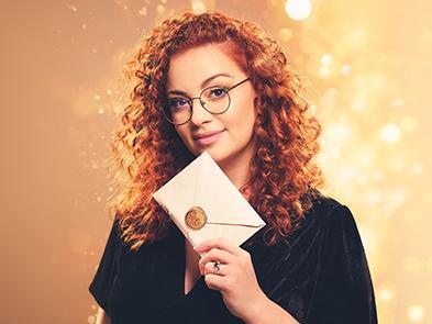 Carrie Hope Fletcher holding a sealed envelope