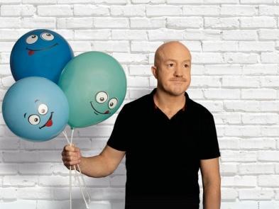 Andy Parsons holding balloons with smiley faces on