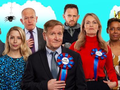 Actors in front of a cartoon of Elizabeth Tower and a cloudy day with a black spider hanging down, left to right Jason Callender, Natalie Dunne,  William Oxborrow, Matthew Cottle, Ryan Early, Debra Stephenson & Krissi Bohn.
