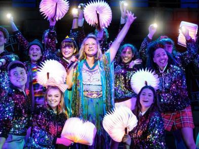 Teacher with fan is surrounded by students with torches