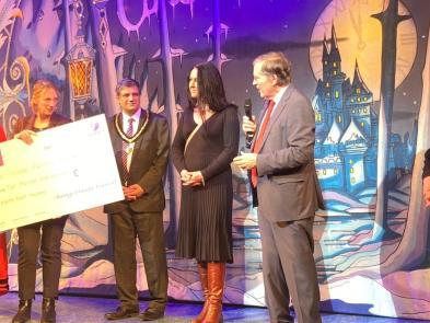 Mayor Masuk Miah, Joanna Read (holding a large cheque), Cllr Saj Hussain, Cllr Denise Turner-Stewart, Stephen Bampfylde & Cllr Fiona Davidson stand onstage before the start of the Cinderella Pantomime  